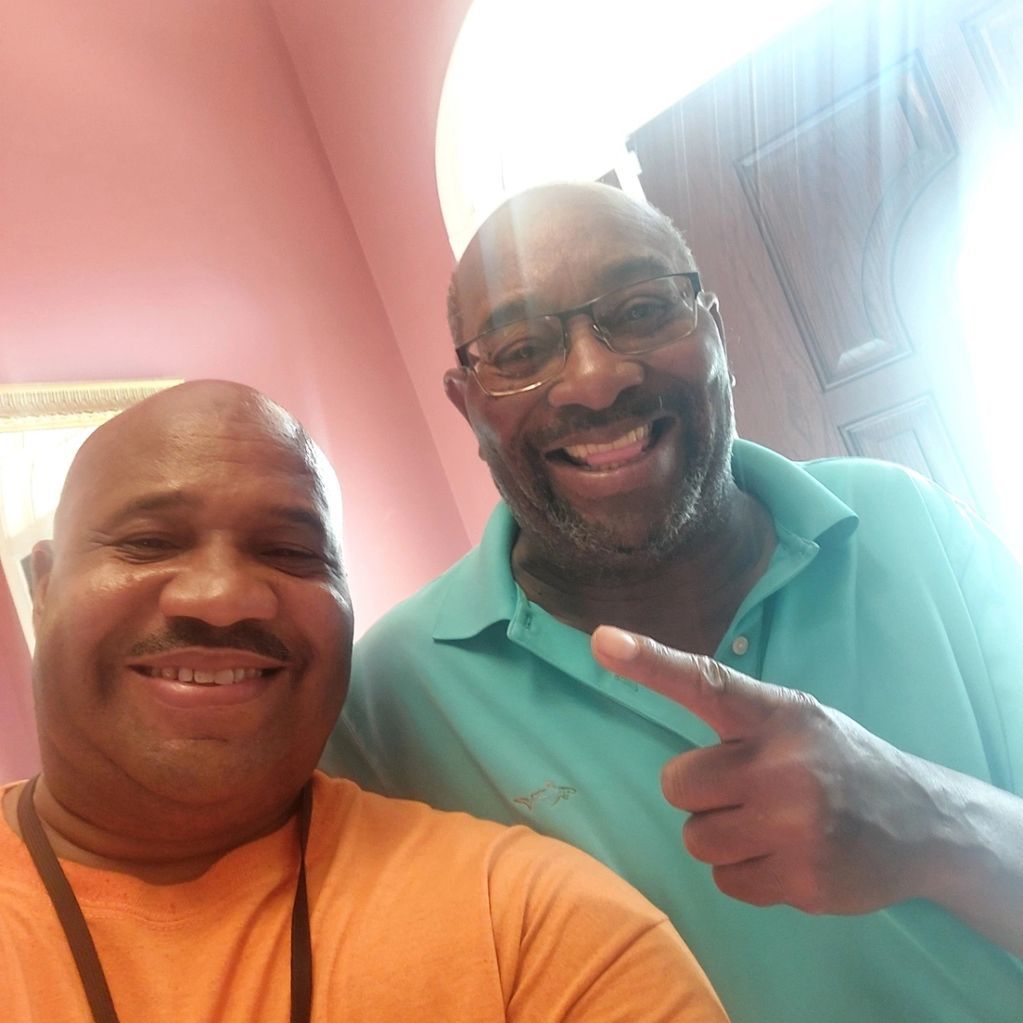 Two men are posing for a picture and one is pointing at the camera.