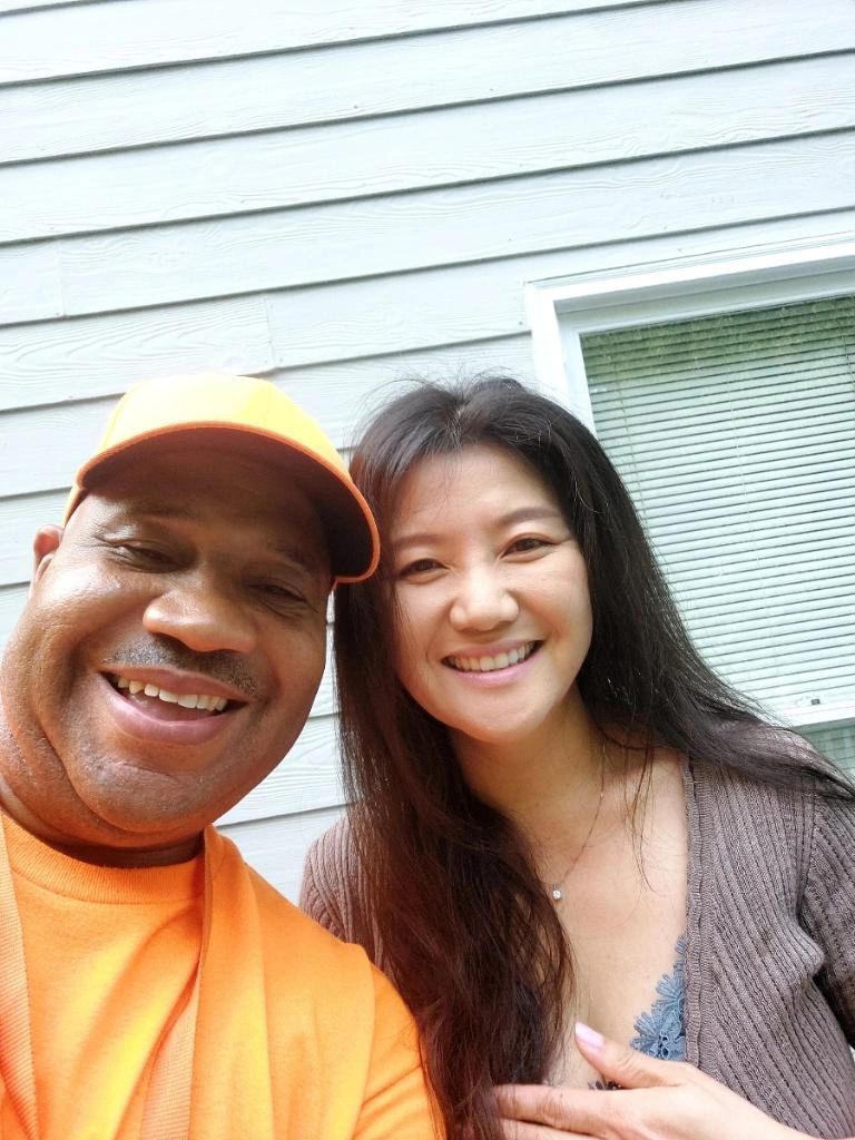 A man and a woman are posing for a picture in front of a house.