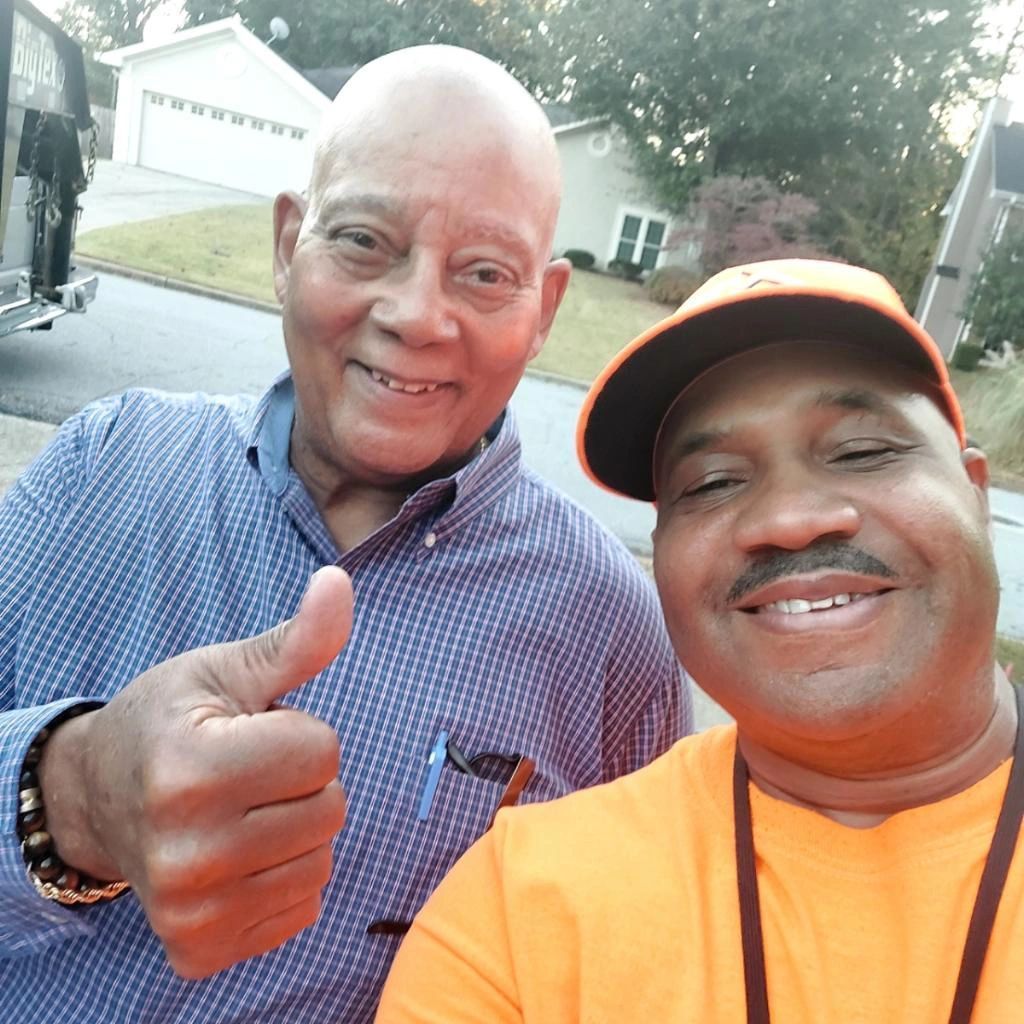 Two men are posing for a picture and one is giving a thumbs up