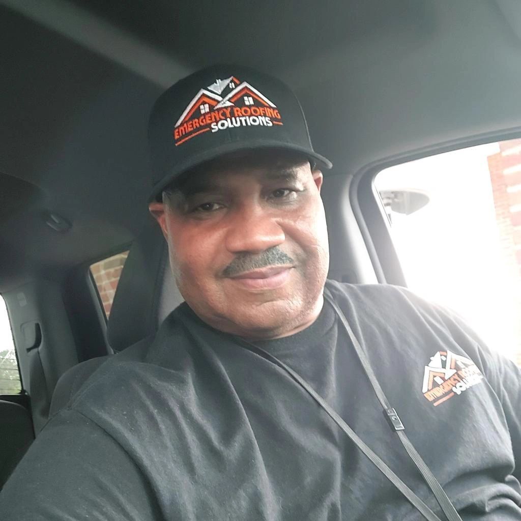 A man wearing a hat and a black shirt is sitting in a car.