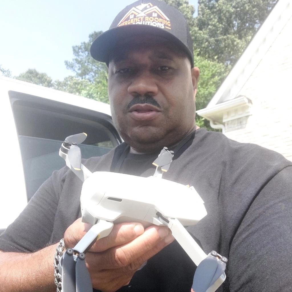 A man wearing a hat is holding a drone in his hands