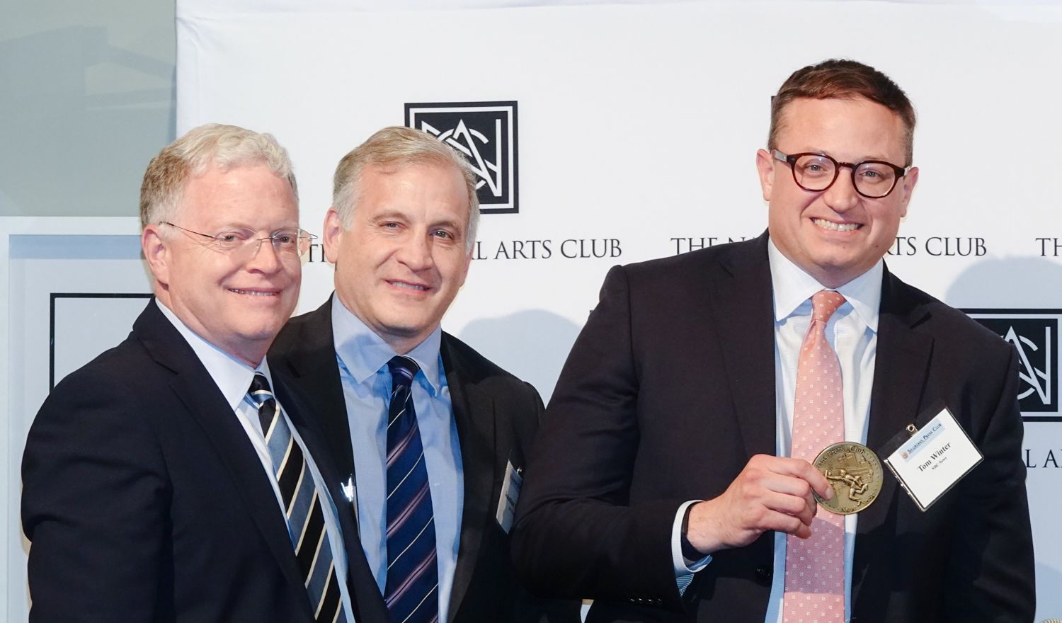 Three men in suits and ties are posing for a picture
