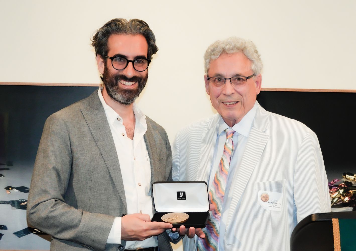 Two men are standing next to each other and one is holding a box