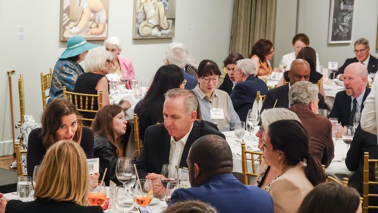 A large group of people are sitting at tables at a dinner party.