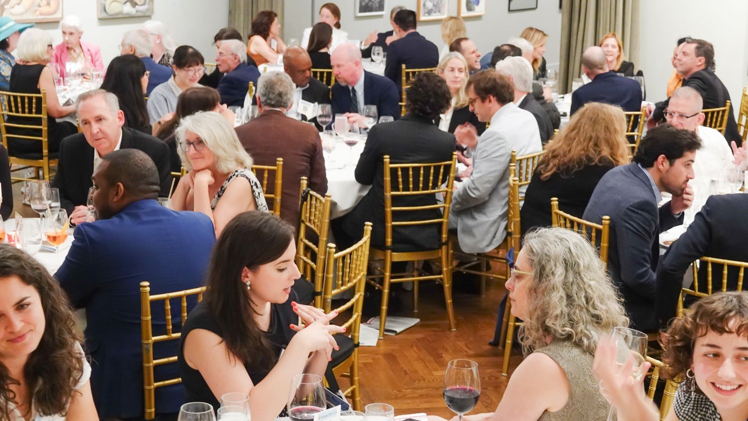 A large group of people are sitting at tables at a dinner party.