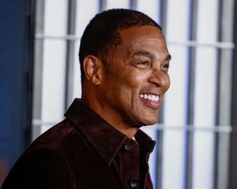 Man smiling, wearing a brown corduroy shirt; indoors with a light blue and white background.