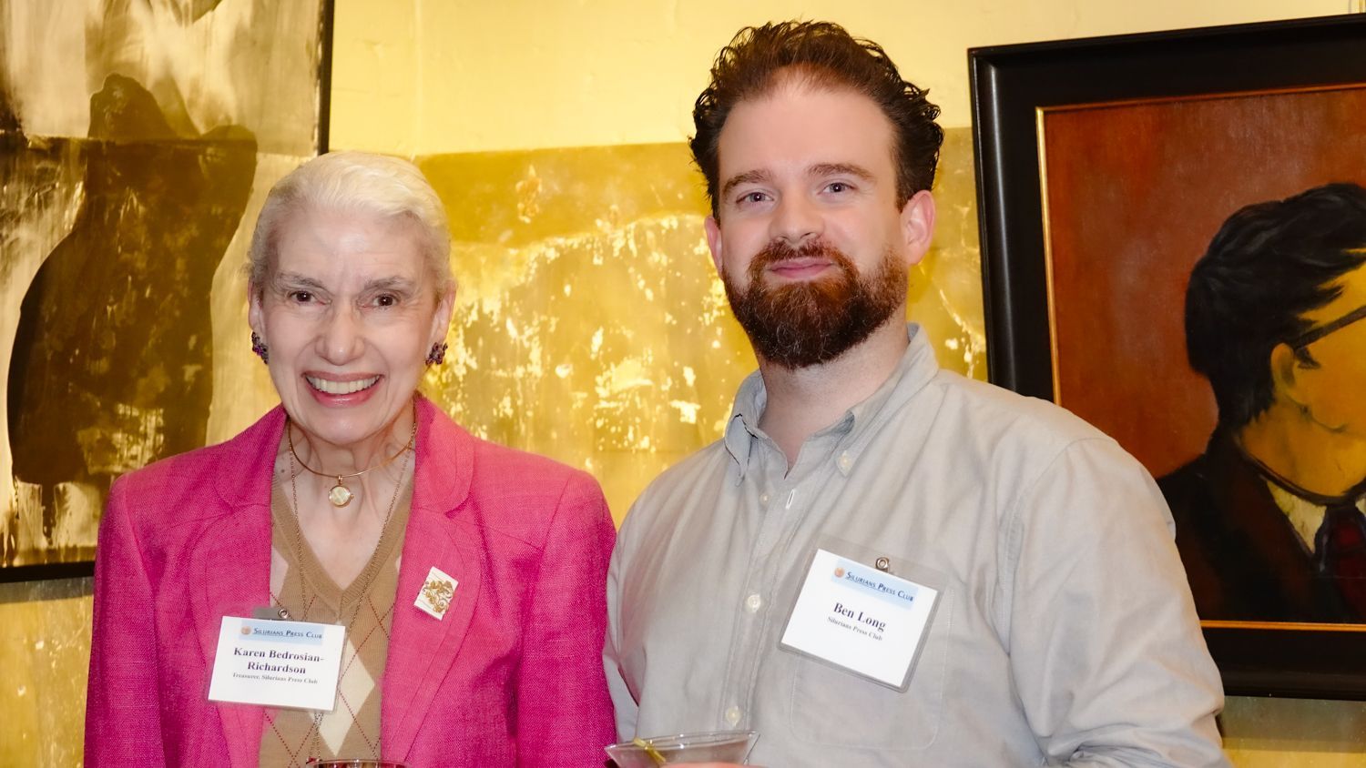 A man and a woman are posing for a picture in front of a painting