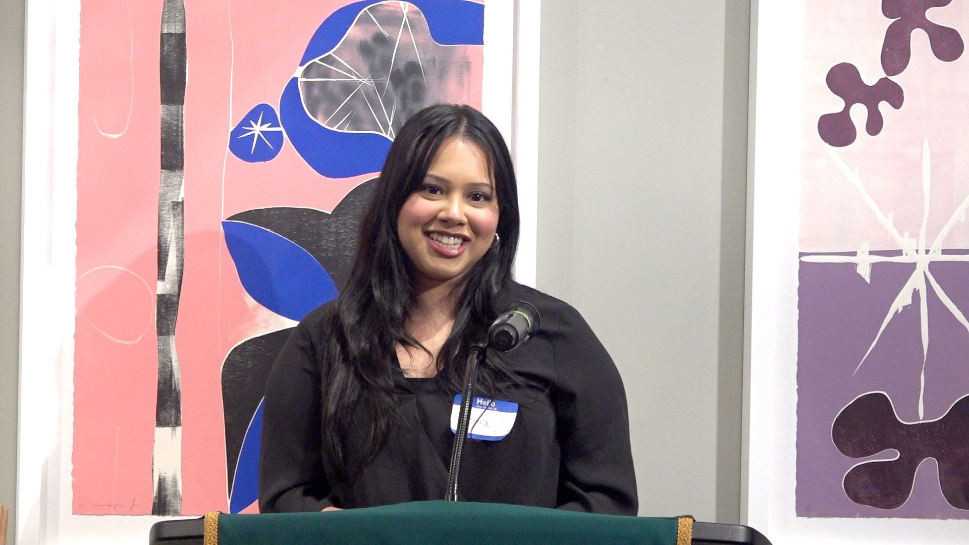 A woman is standing at a podium in front of a microphone.