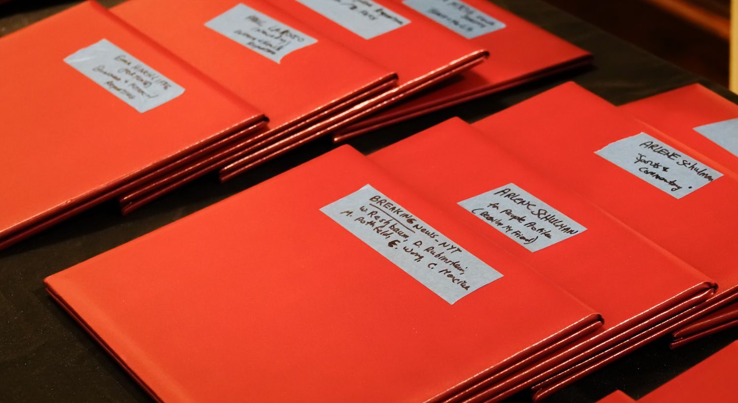 A stack of orange envelopes with white labels on them