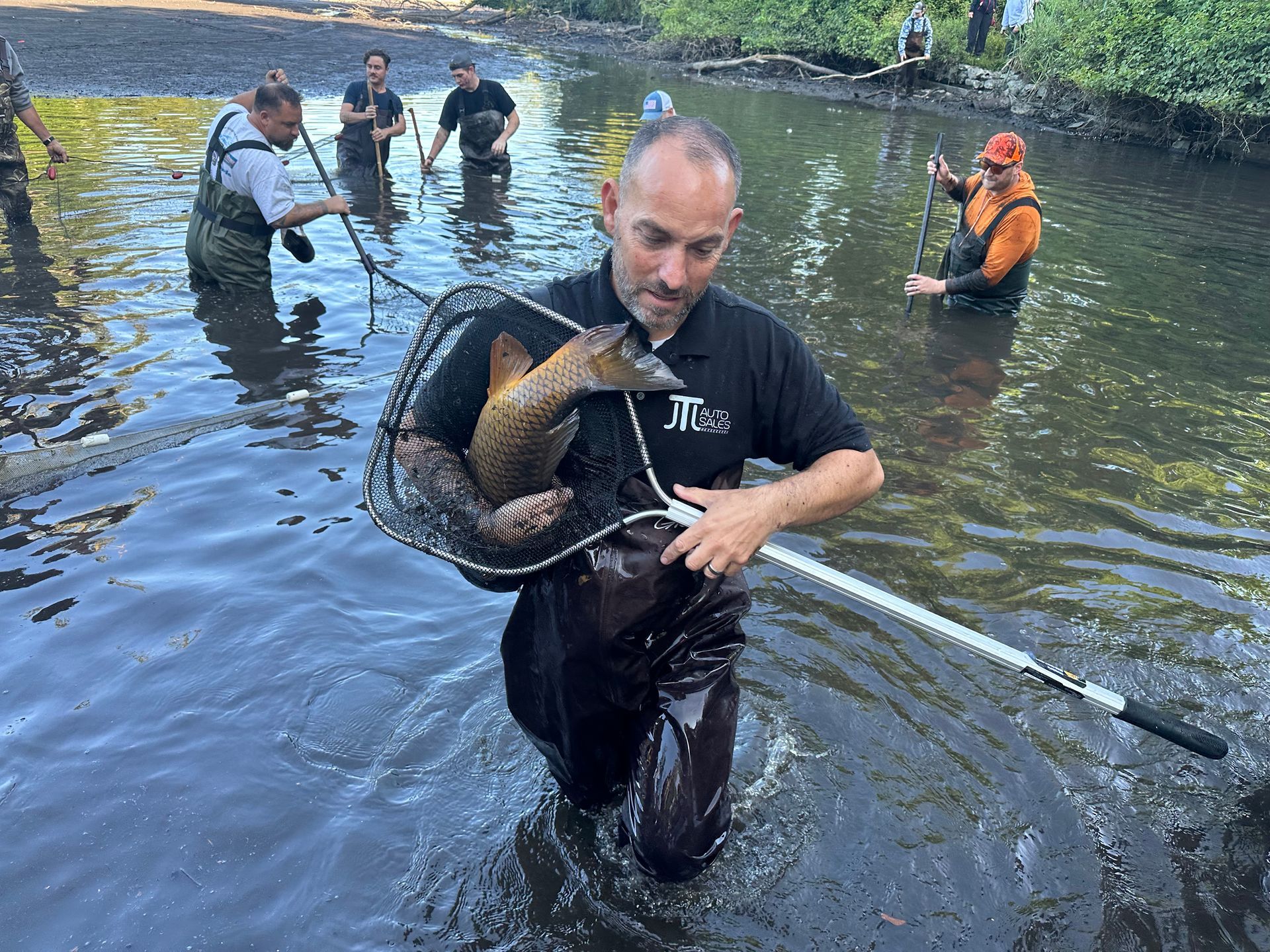 A man is holding a fish in a net in the water.
