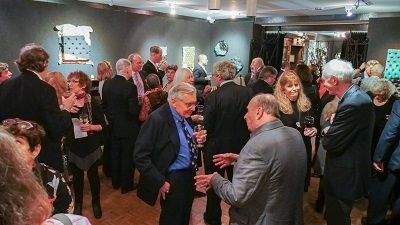 A group of people are standing in a room talking to each other.