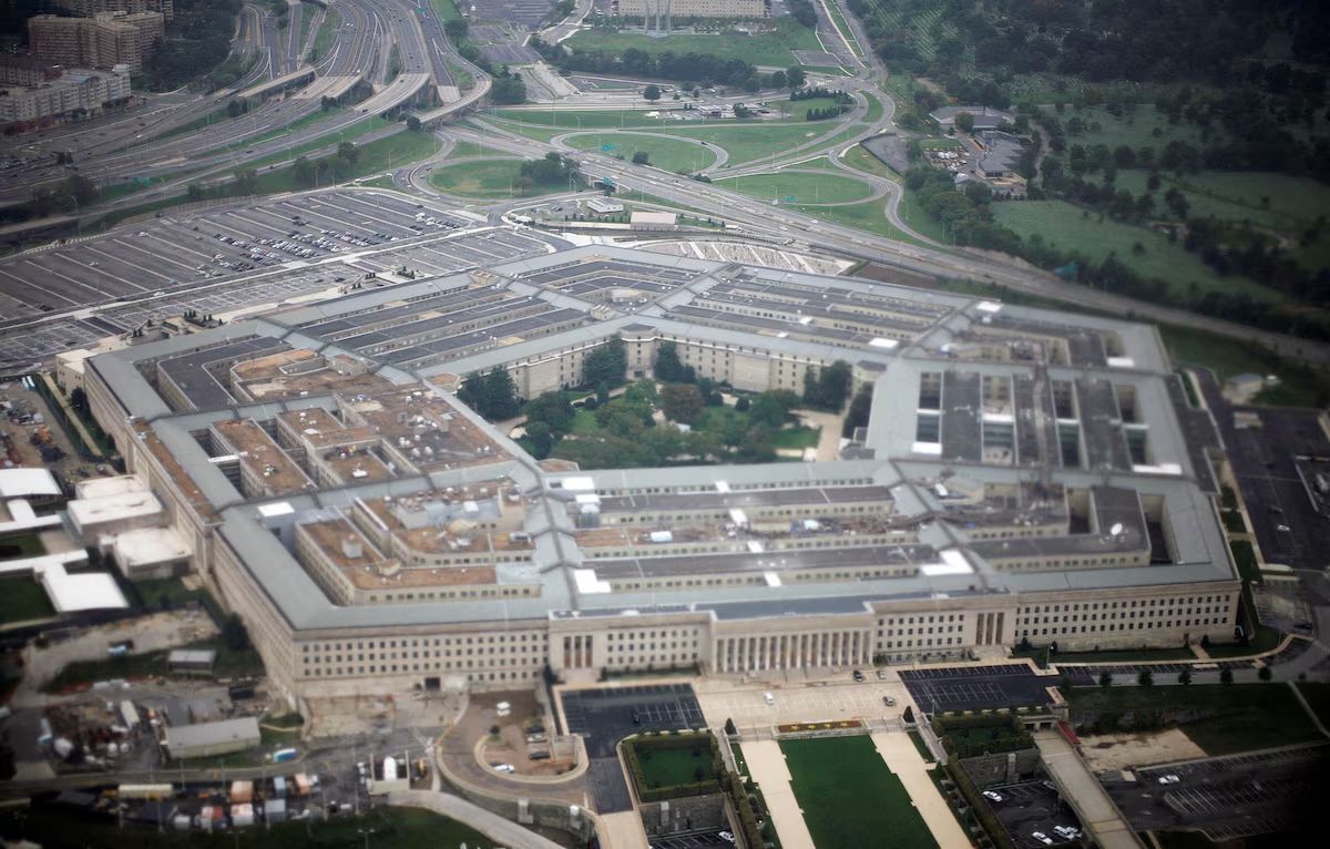 Aerial view of The Pentagon building in Arlington, Virginia, situated near a river with trees and surrounding cityscapes.