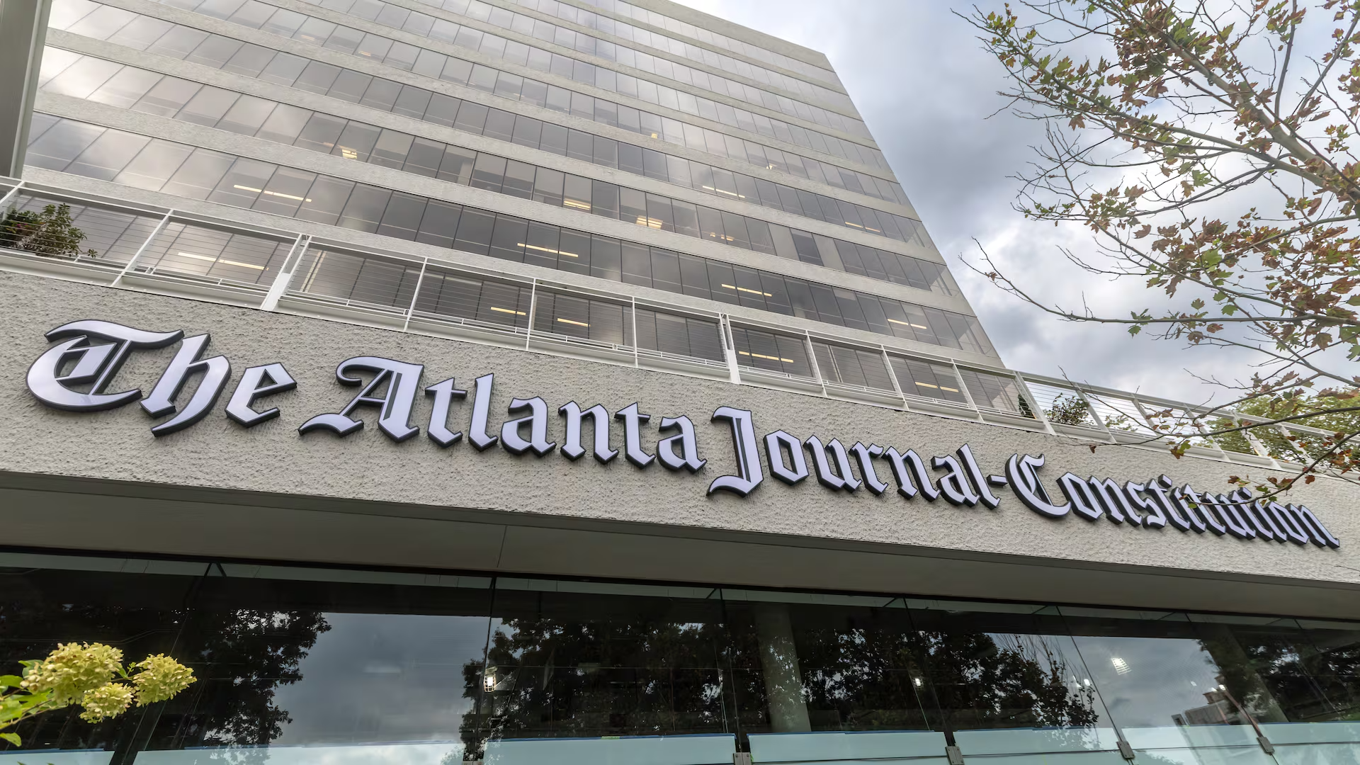 "The Atlanta Journal-Constitution building with a modern, glass exterior and the newspaper's sign."