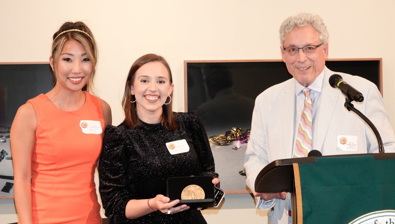 A man and two women are standing next to each other at a podium.