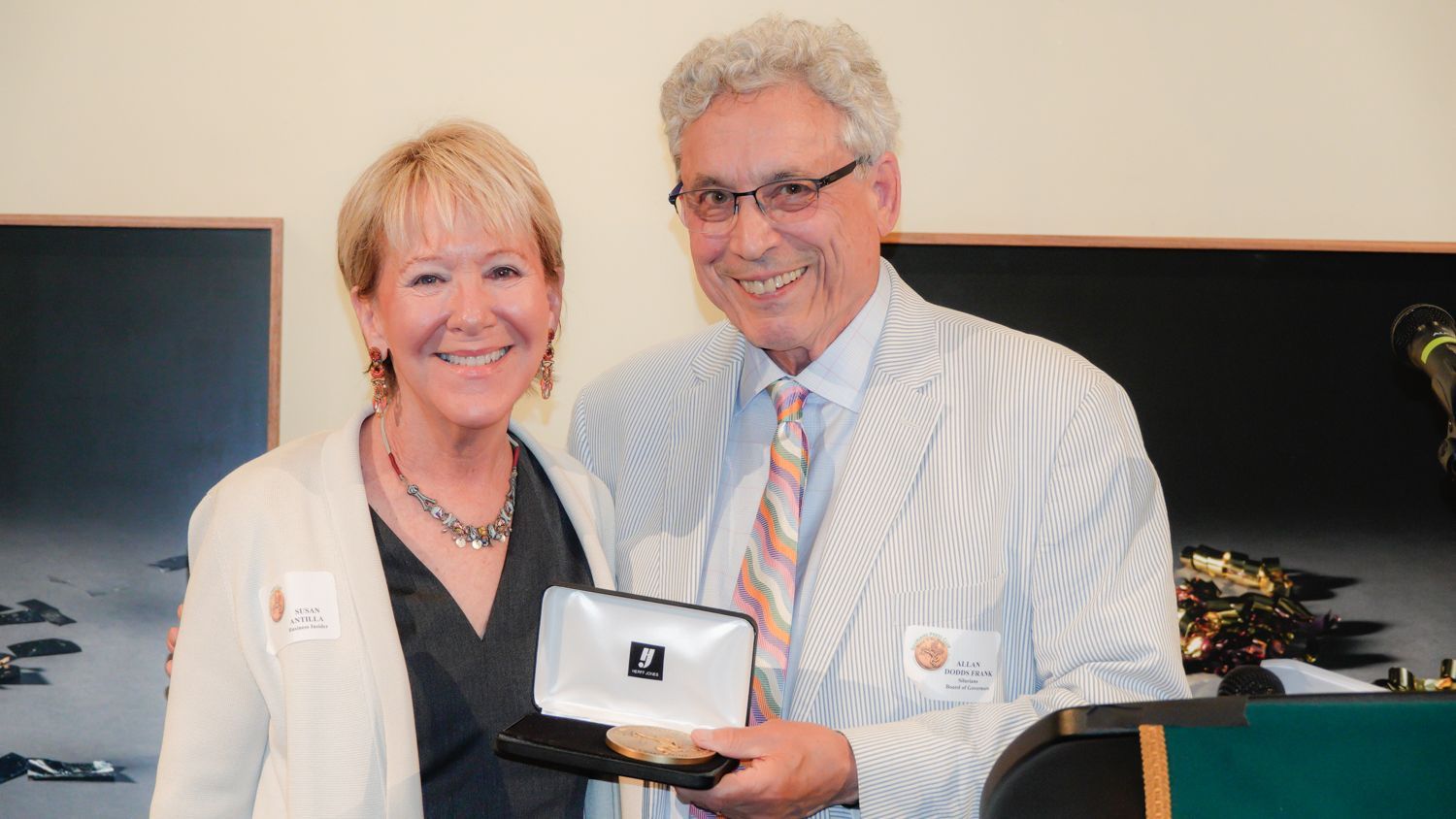 A man and a woman are posing for a picture and the man is holding a plaque