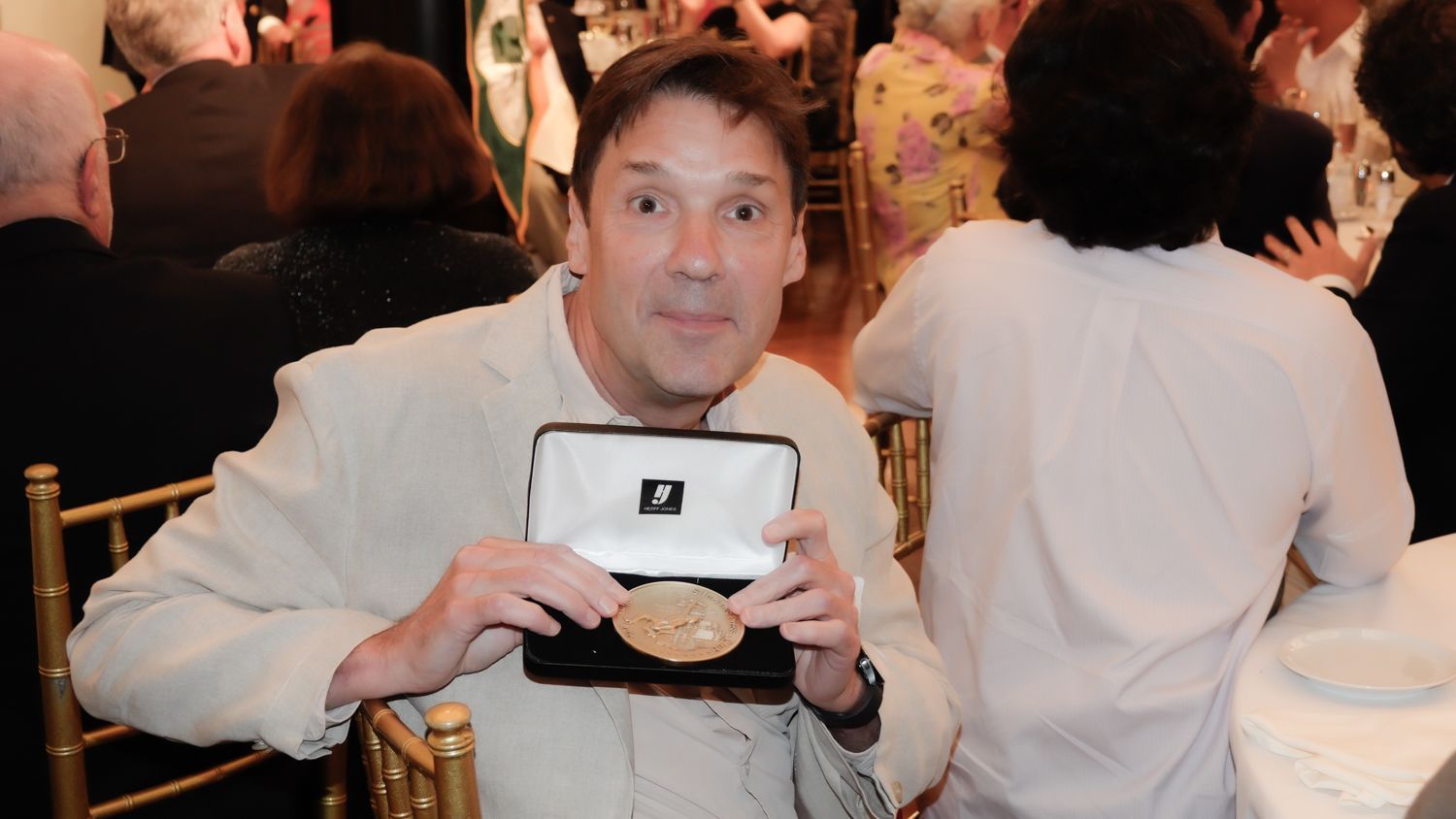 A man is sitting in a chair holding a medal in a box
