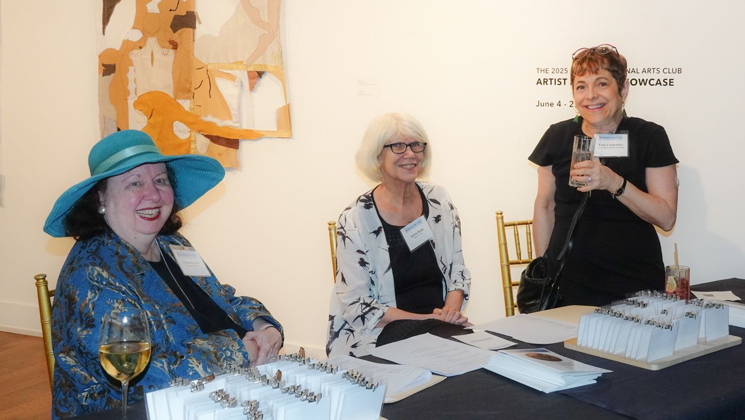 Three women are sitting at a table holding glasses of wine