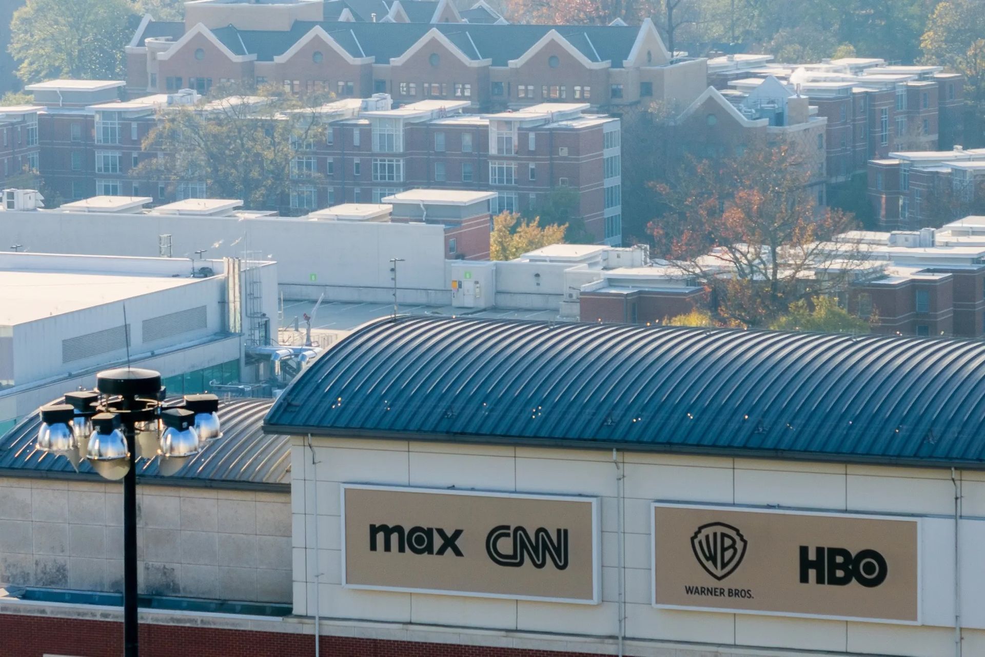 Building exterior with "max CNN" and "WB HBO" signs; cityscape background.