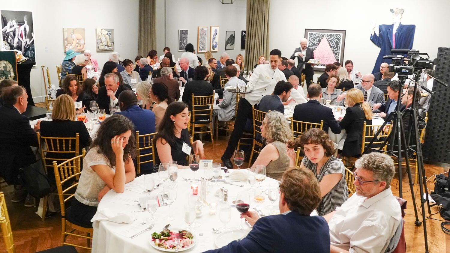 A large group of people are sitting at tables in a room.