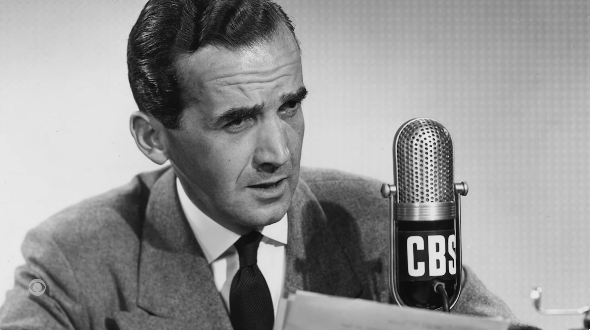 Man speaking at a CBS microphone in a black-and-white photo