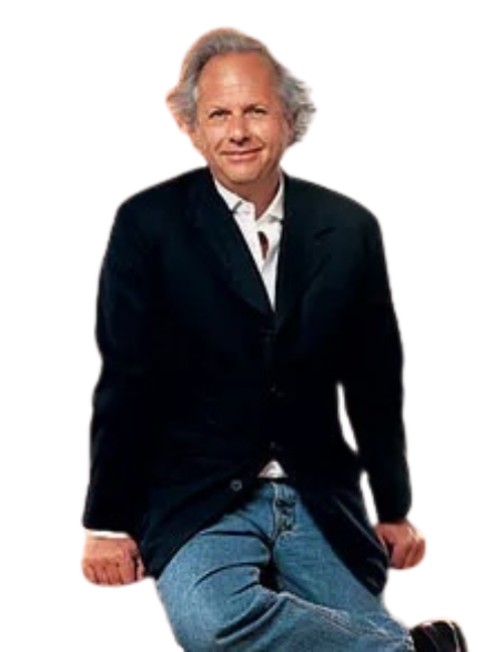 A person with gray hair wearing a dark blazer and white shirt stands with hands in their pockets against a gray backdrop.