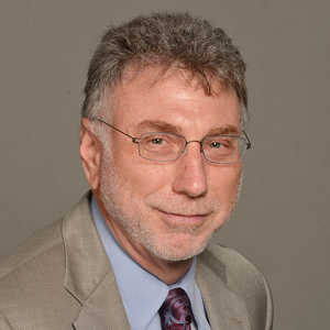 A man in a suit and tie is smiling for the camera