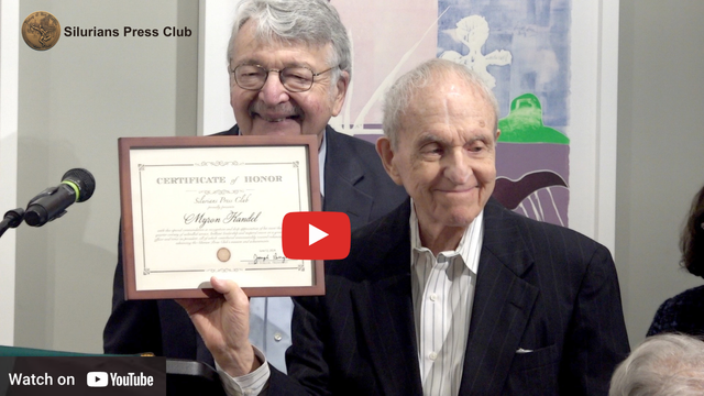 Two men are holding a certificate in front of a microphone.