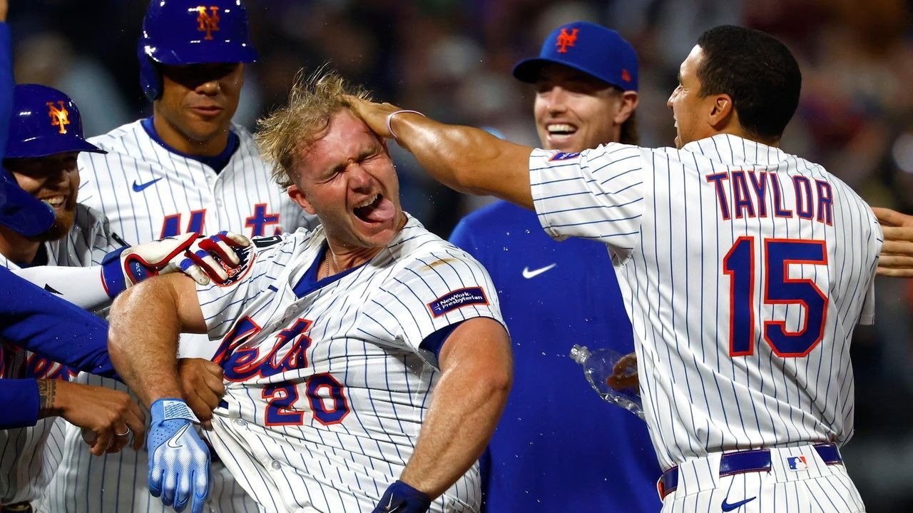 New York Mets players celebrate a win, dousing a teammate in water on the field