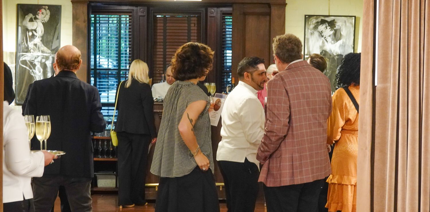 A group of people are standing in a room talking to each other.