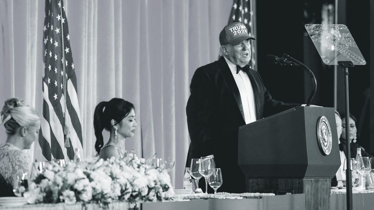 Speaker at podium during formal banquet, with U.S. flag and seated attendees nearby.