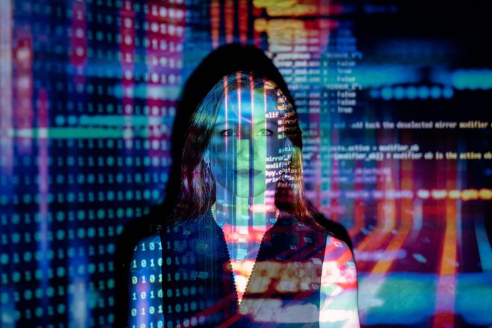 A double exposure of a woman 's face and a computer screen.