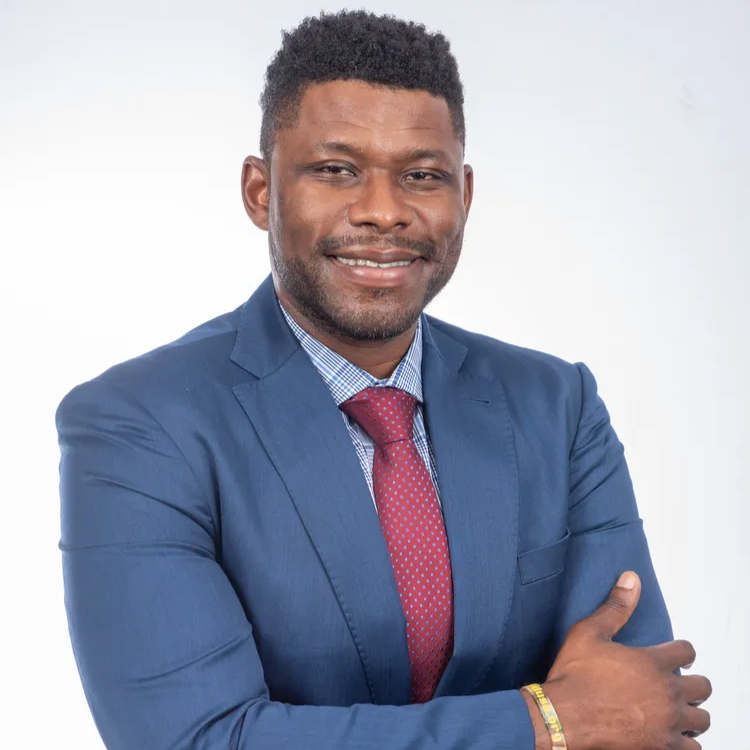 Man in blue suit, red tie, smiling; studio shot.