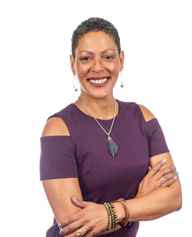Woman with short hair, smiling, arms crossed, wearing a purple dress and jewelry, against a white background.