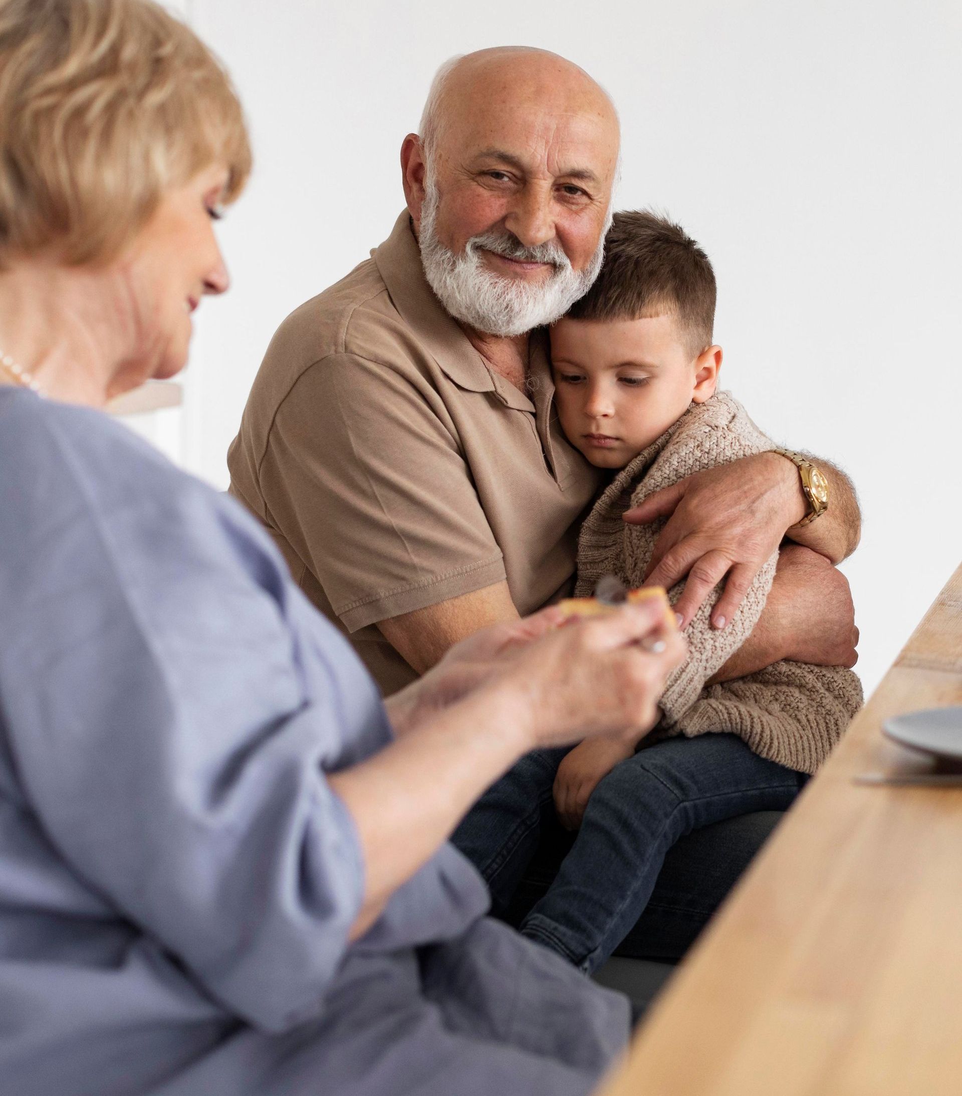 A man with a beard is holding a child while sitting at a table.