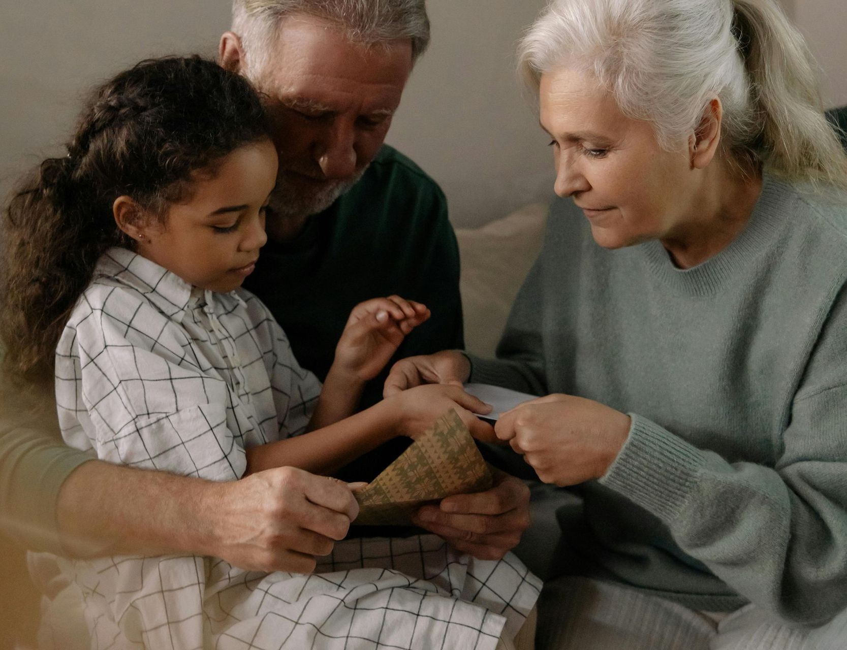 A man and woman are sitting on a couch with a little girl.