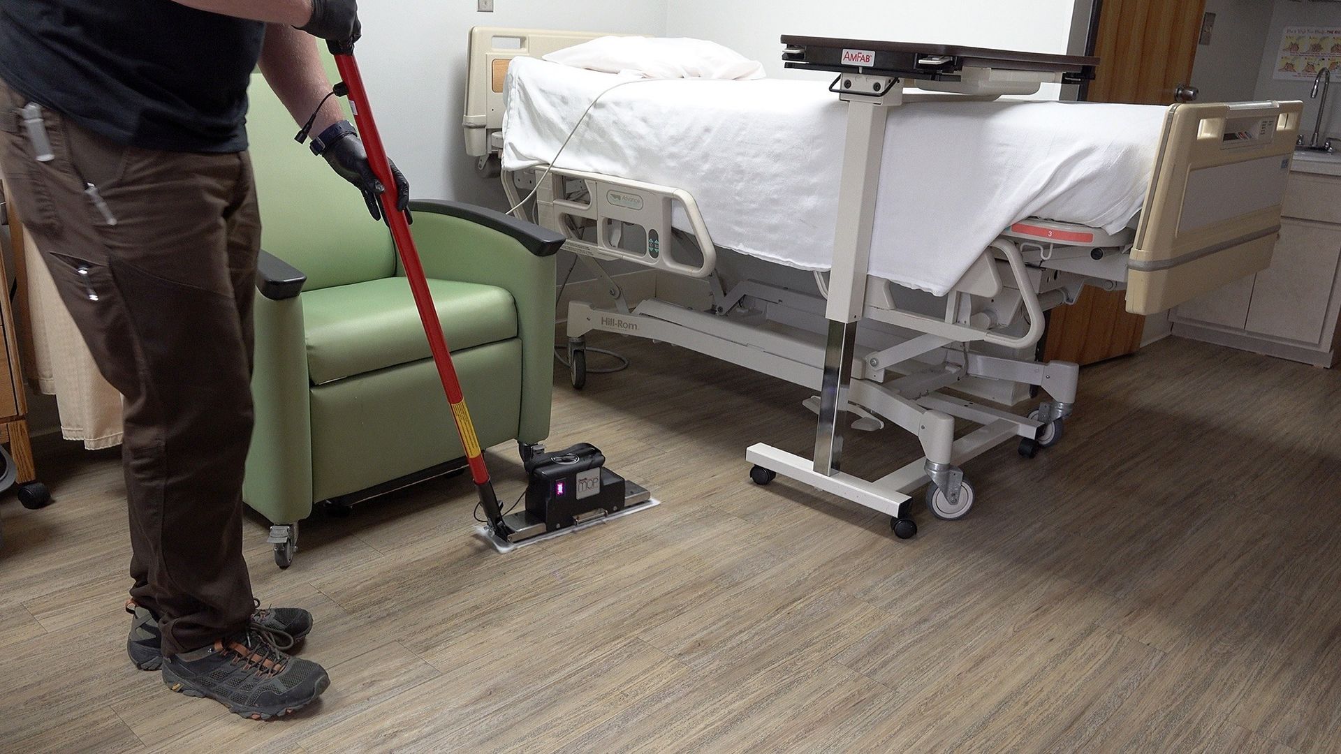 A man is mopping the floor of a hospital room.