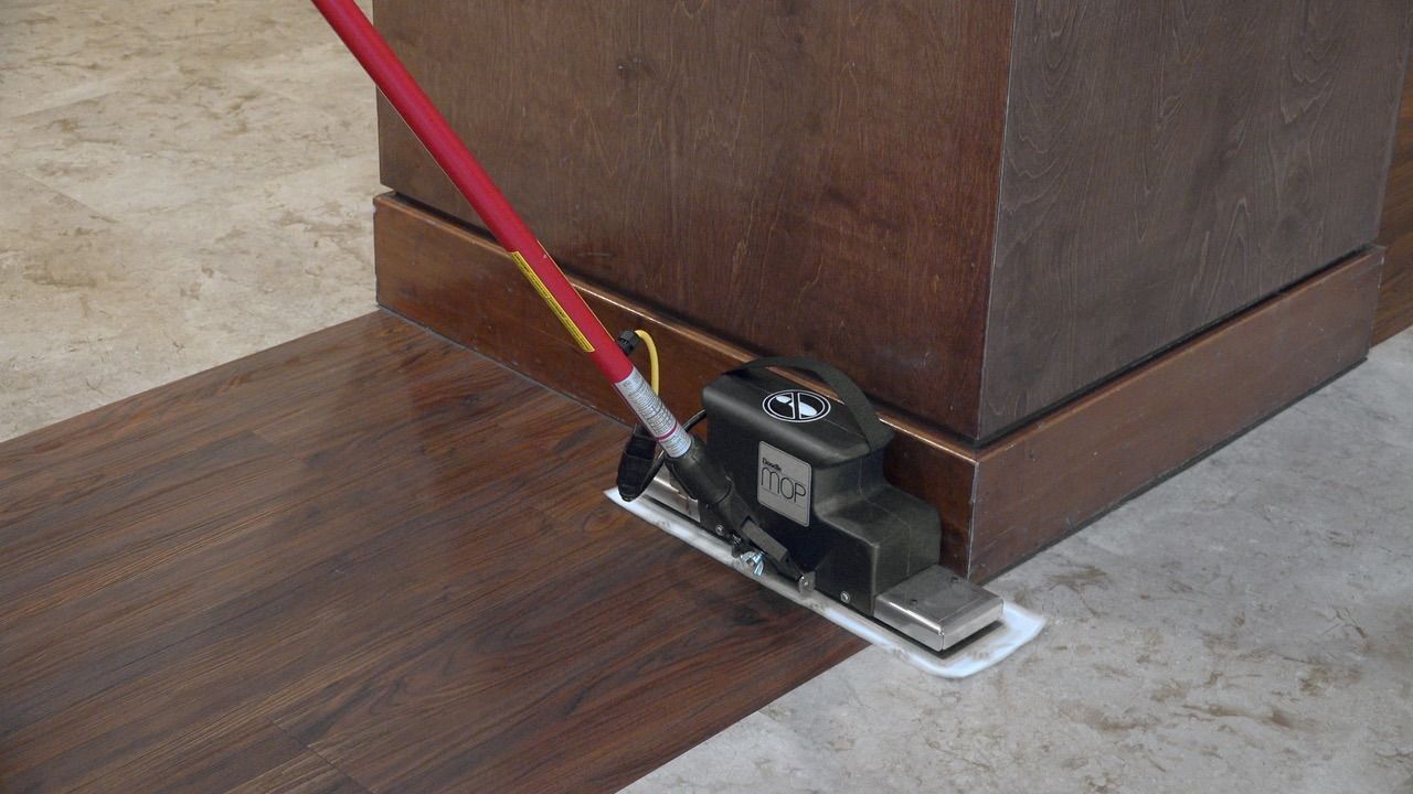 A mop is being used to clean a wooden floor.