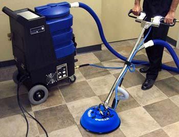 A person is using a machine to clean a white tile floor.