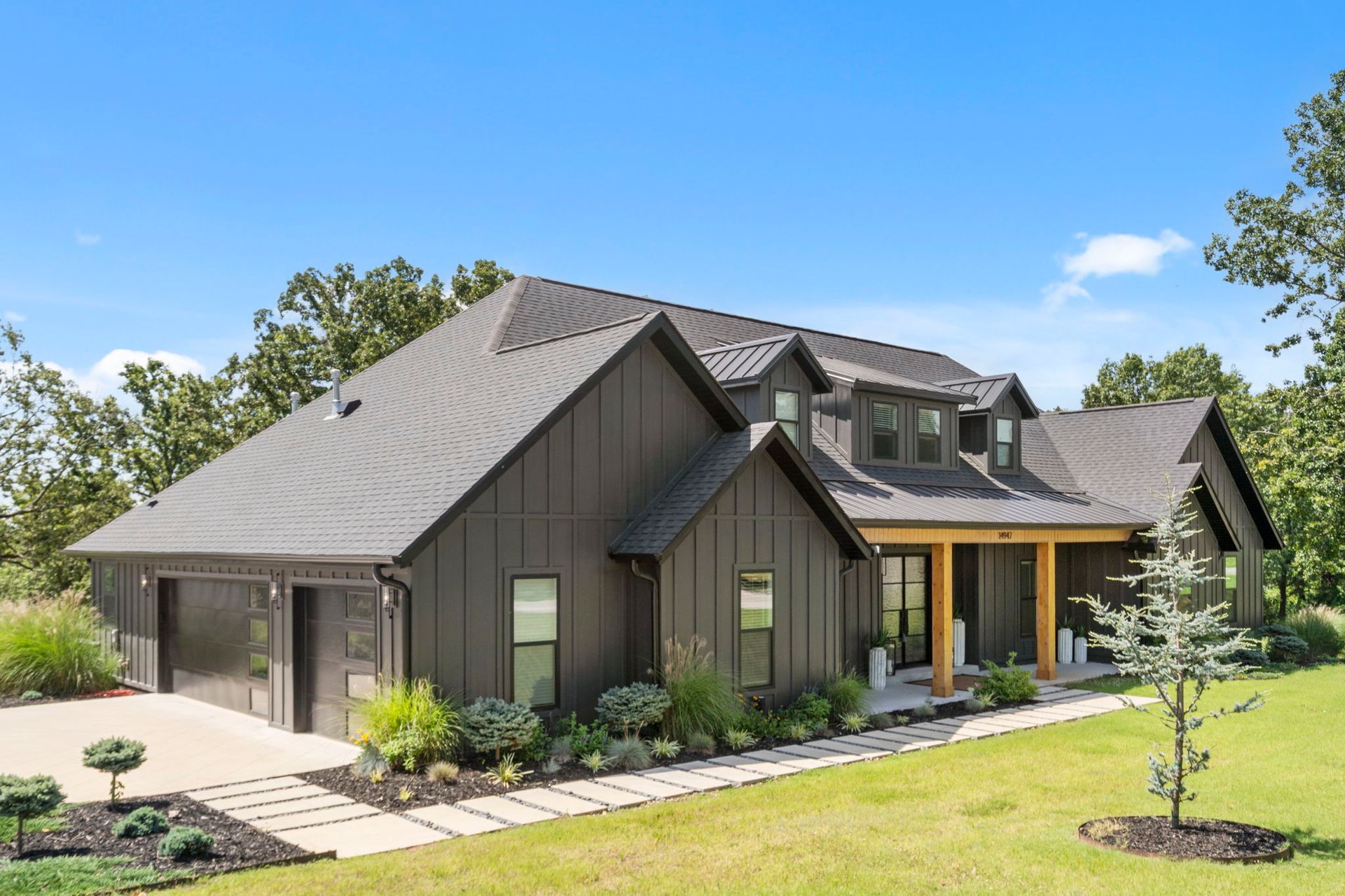 A large house with a gray roof is sitting on top of a lush green field.
