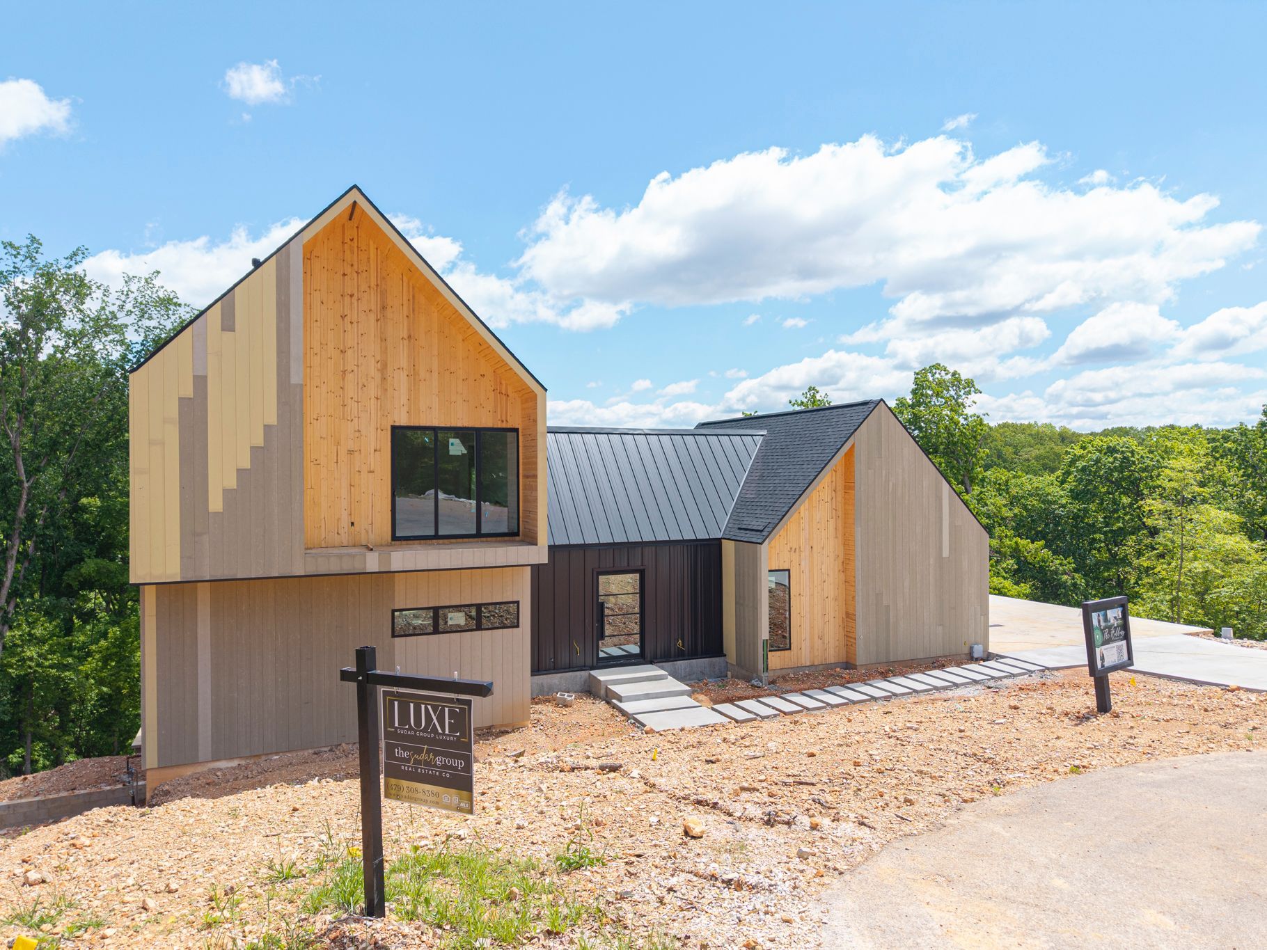 A house with a for sale sign in front of it is sitting on top of a dirt hill.