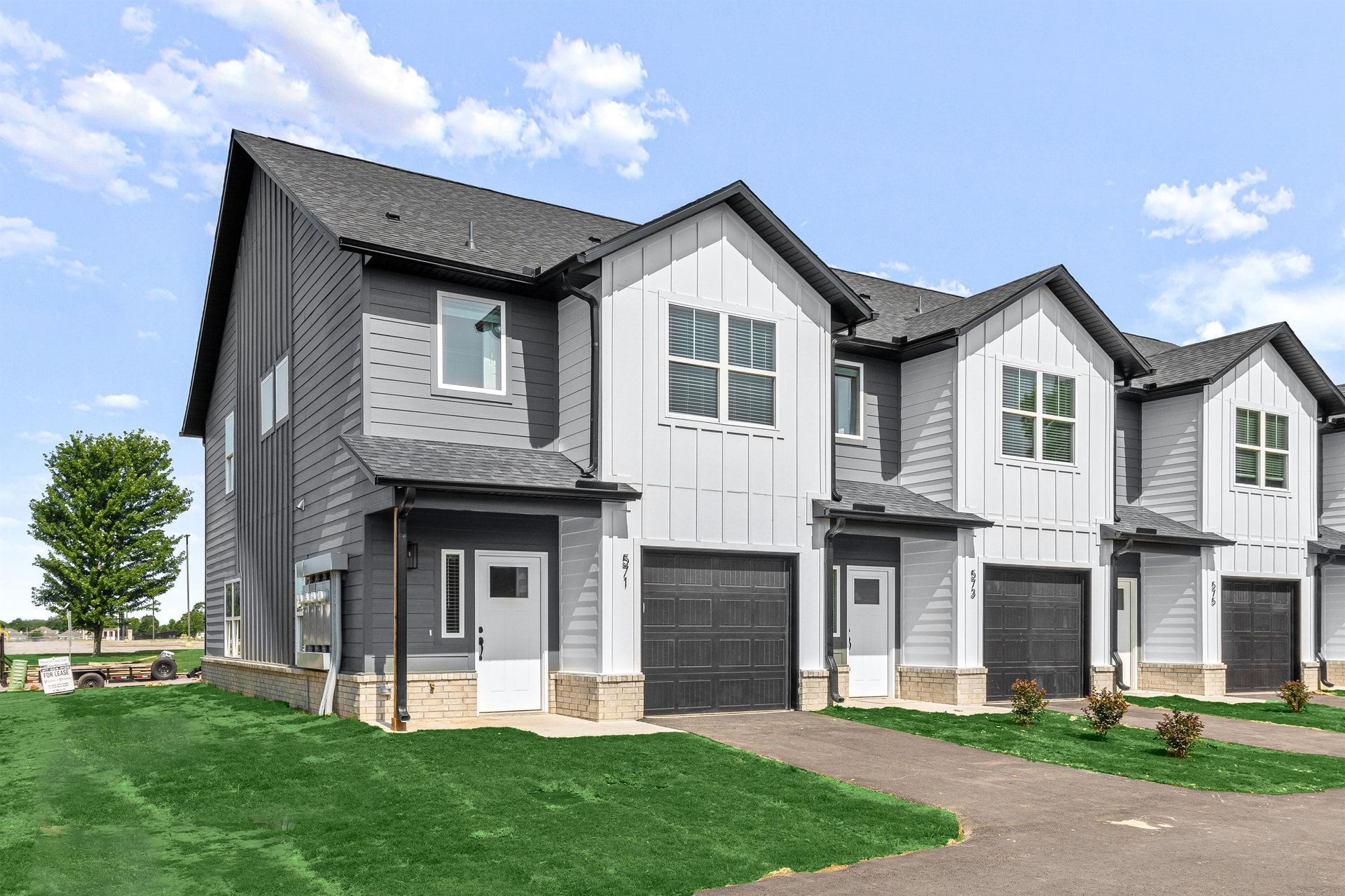 A large white house with a black garage door is for sale.
