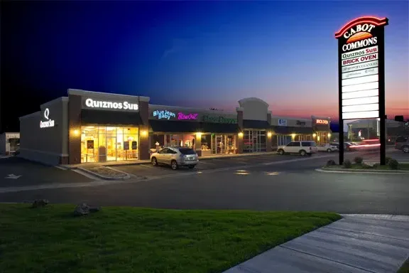 A car is parked in front of a store called queens inn