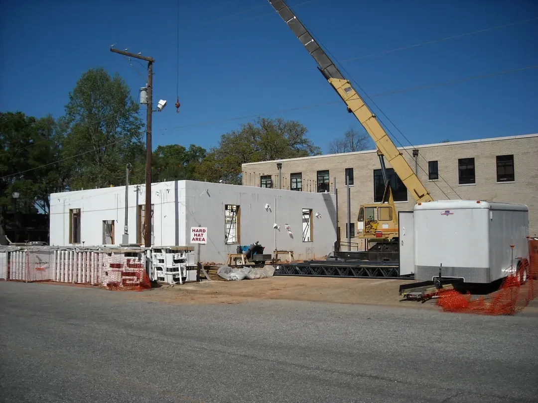 A construction site with a yellow crane in front of a building