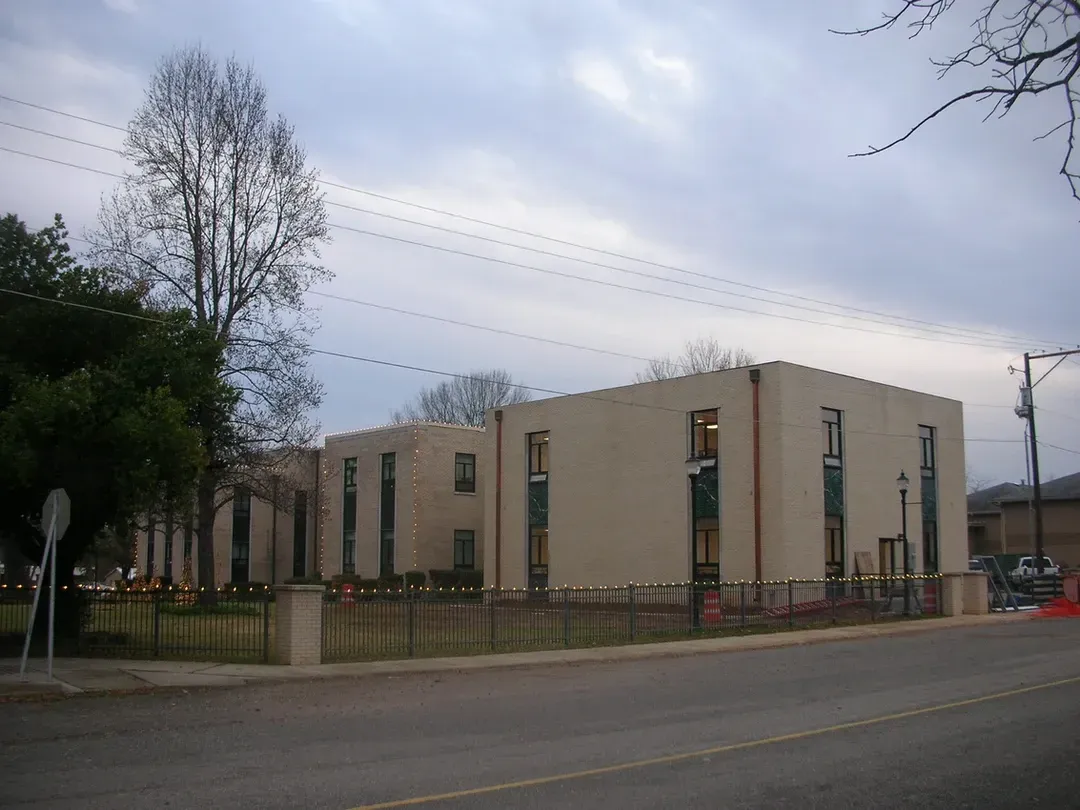 A large building with a lot of windows is next to a street