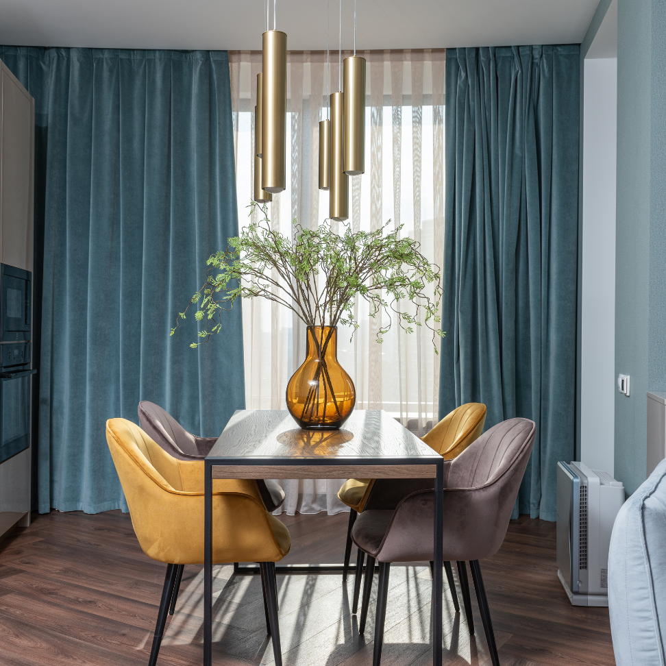 A dining room with a table and chairs and a vase of flowers on it.