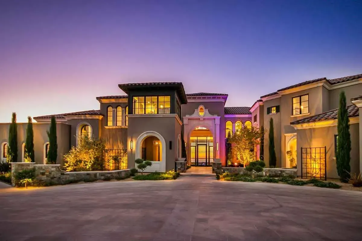 A large house with a lot of windows is lit up at night.