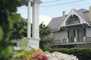 A large white house with a porch and flowers in front of it.