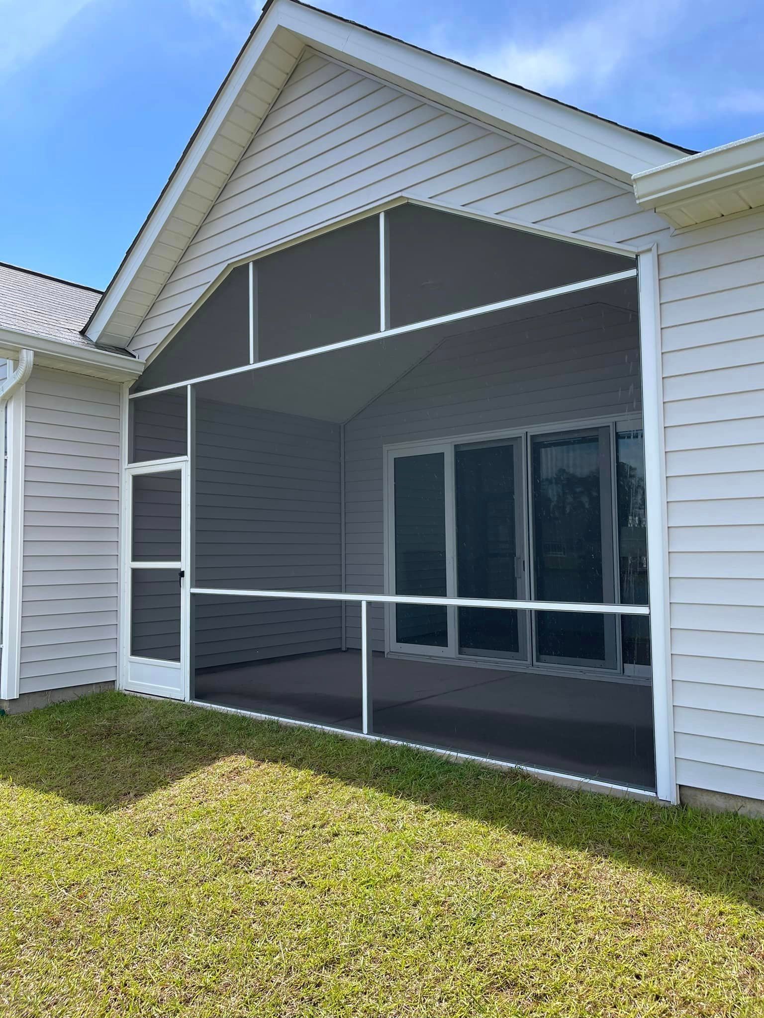 A screened in porch on the side of a white house in Coastal Carolina.