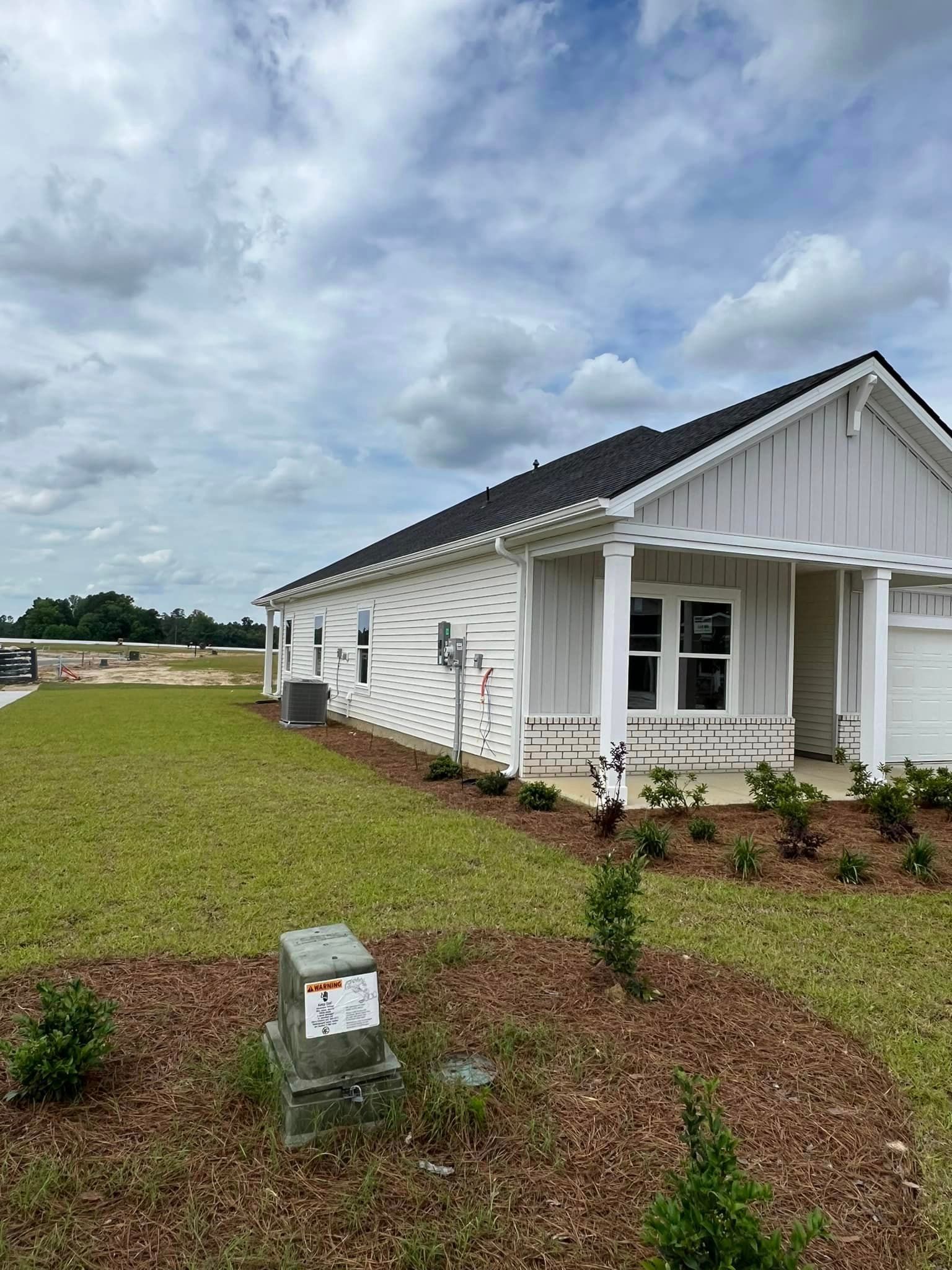 A small house with a porch, a lot of grass in front of it and newly repaired gutter in Coastal Carolina