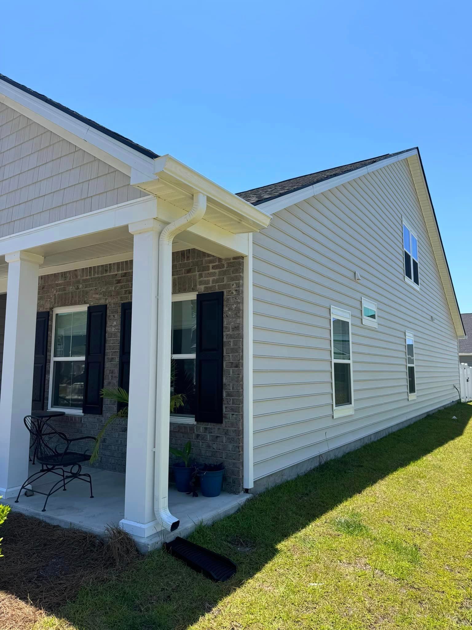 A white house with newly installed gutter and leaf guard in Mullins SC.